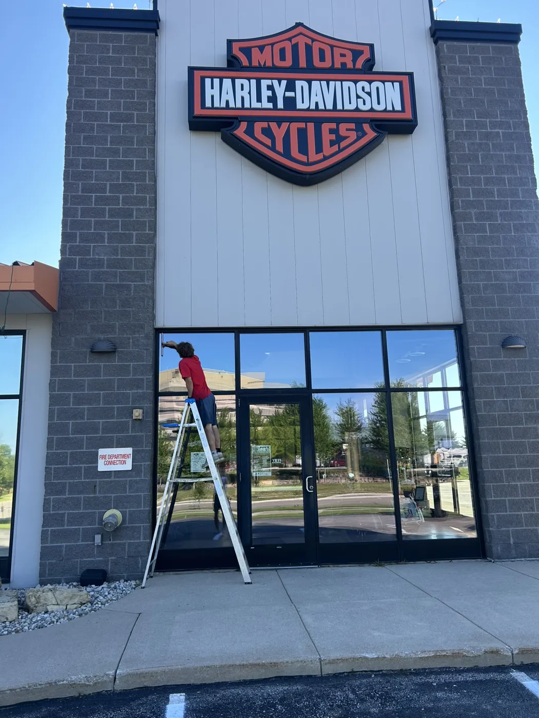 Technician cleaning storefront windows at a commercial property