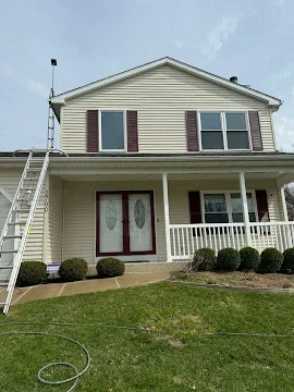 Technician setting up a ladder to soft-wash a home exterior