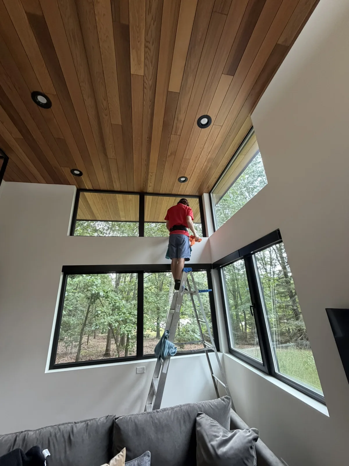 Technician cleaning interior windows on a ladder